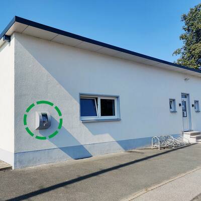 Der Defibrillator (AED) ist an der Außenwand des Sportheims in Heßdorf angebracht und öffentlich zugänglich.